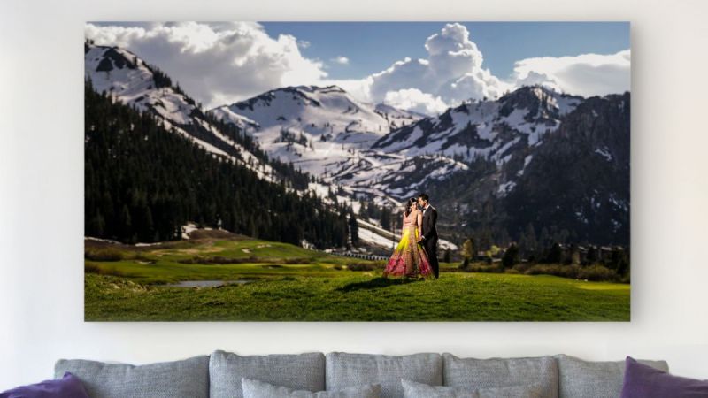 couple stands in front of mountains or large photo prints